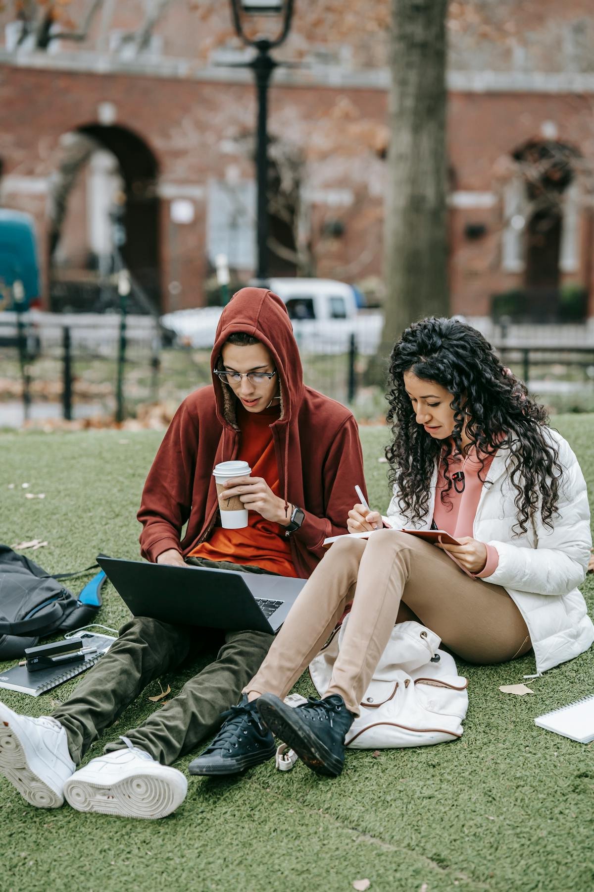 Students sitting outdoors and reviewing university materials together